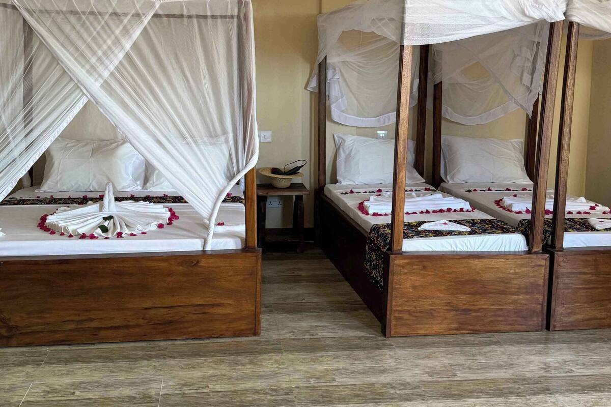 A room with two wooden beds, each with a canopy.