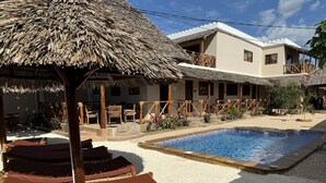 Un área de piscina con sillas de descanso y una estructura de techo de paja.