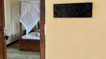Quarto com uma cama, moldura de porta de madeira e placa na parede com o número 5.