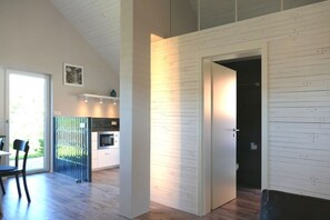 A modern kitchen with white cabinetry, a built-in oven, and a dining area with a table and chairs. - Modern detached vacation home for two on the edge of the village in the Bavarian Rhön. (Ostheim vor der Rhön)