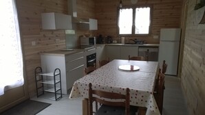 Una cocina compacta con paredes de madera, una mesa de comedor con mantel de lunares y electrodomésticos básicos.