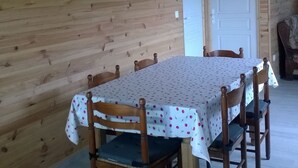 Una habitación con paneles de madera y una mesa de comedor preparada para cuatro personas, rodeada de sillas.