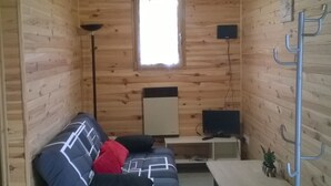 Una habitación acogedora con detalles de madera, un sofá, una mesita, una lámpara de pie y una ventana.