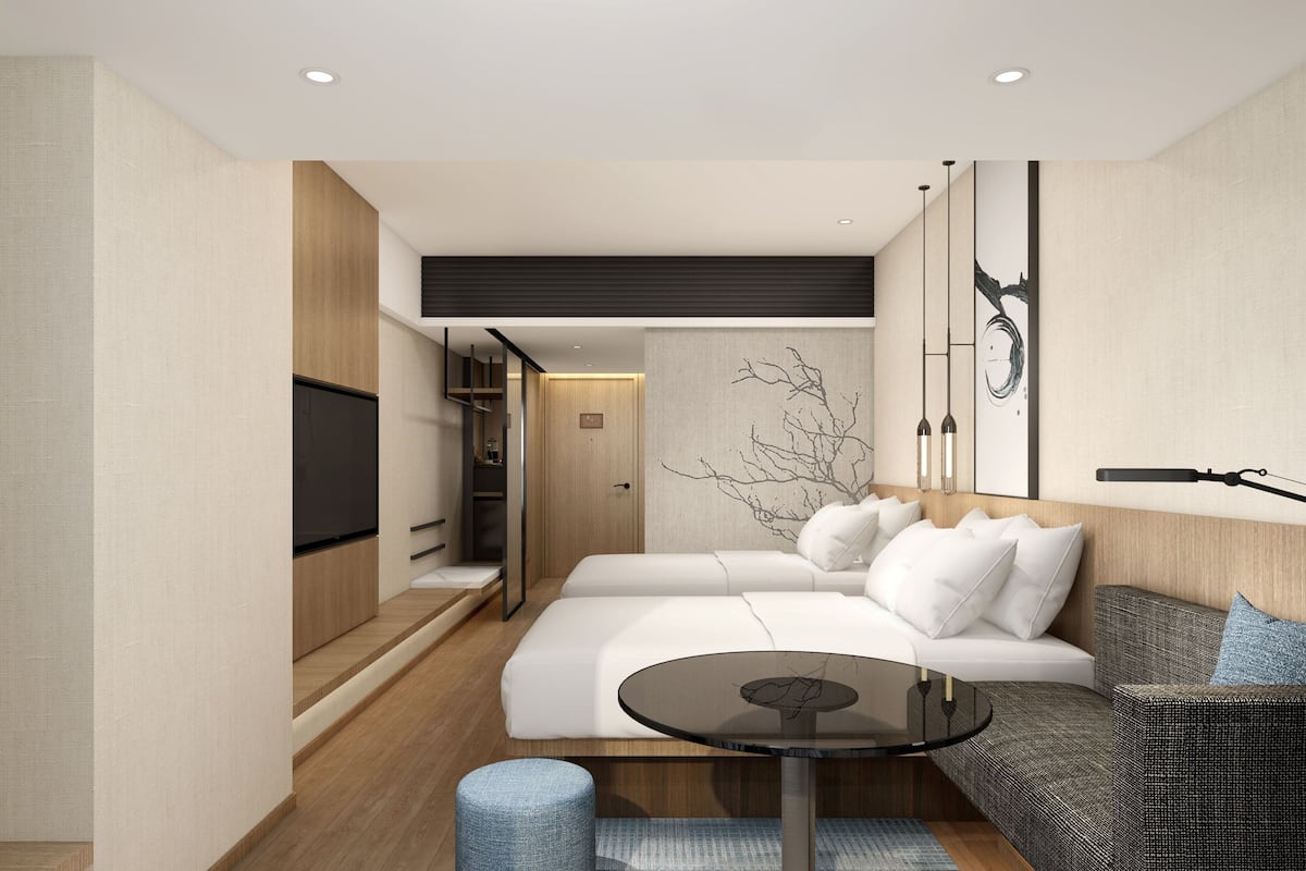 Ein modernes Hotelzimmer mit einem großen Bett, einer Couch, einem kleinen Tisch und einem Fernseher.