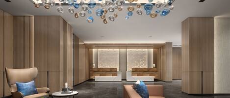 A modern lobby with a seating area, a decorative ceiling, and a reception desk.