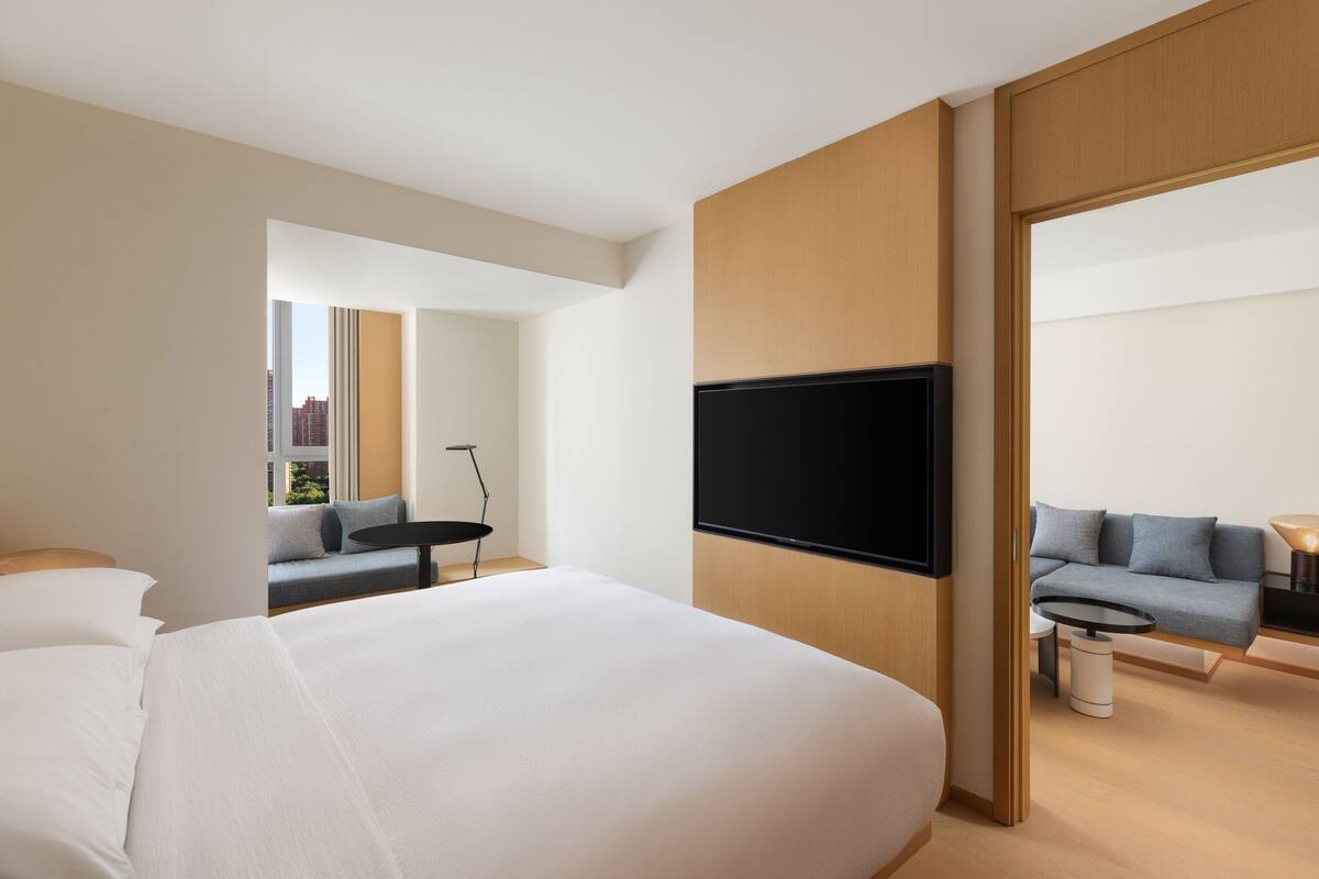 Ein modernes Hotelzimmer mit einem großen Bett, einem wandmontierten Flachbildfernseher, einer Couch und einem kleinen Tisch.