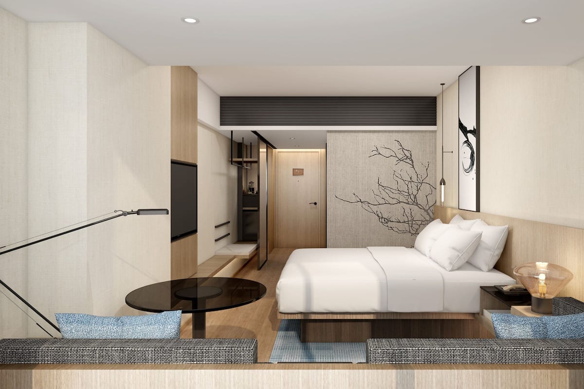 Ein modernes Hotelzimmer mit einem Bett, einem kleinen Tisch, einer Couch und einem Fernseher.