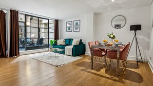 Un salon moderne avec un canapé de couleur turquoise, une table à manger avec des chaises roses et une grande fenêtre agrémentée de rideaux.