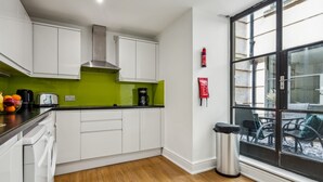 Une cuisine moderne avec des armoires blanches, un pare-feu vert et une grande fenêtre donnant sur un patio.