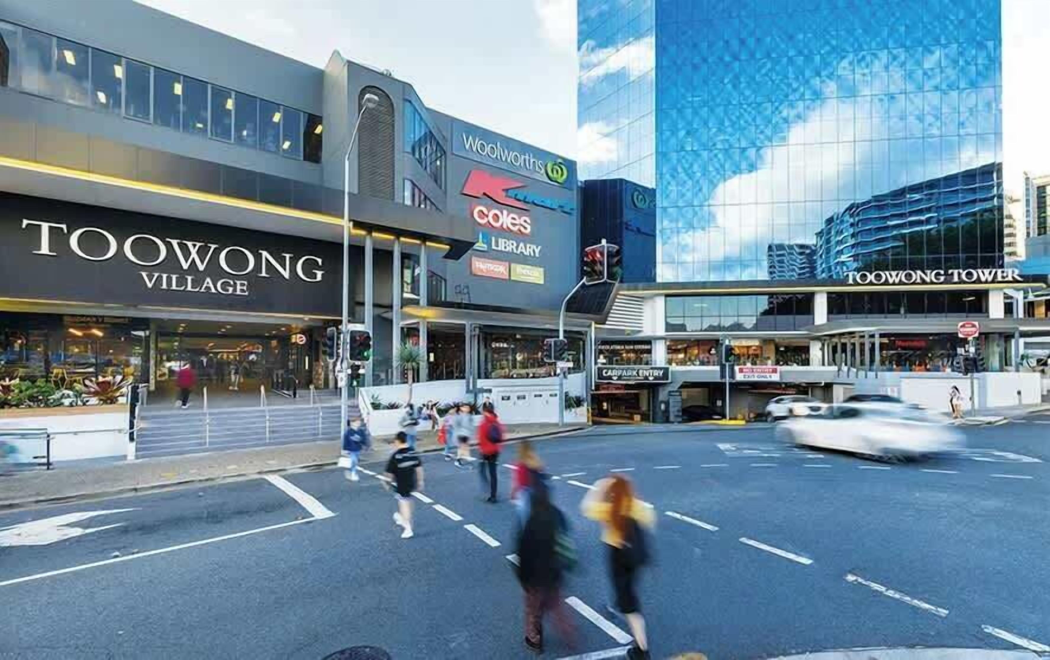 Straßenansicht mit einem Geschäft im Toowong Village, einem Woolworths Schild und dem Toowong Tower Gebäude.