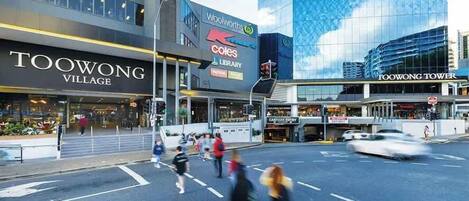 Straßenansicht mit einem Geschäft im Toowong Village, einem Woolworths Schild und dem Toowong Tower Gebäude.