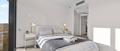 Camera da letto moderna con un letto grande, comodini e vista dalla finestra.