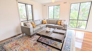 Un salon spacieux avec un canapé d’angle, une table basse et un grand tapis.