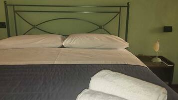 Een net opgemaakt bed met witte lakens en twee opgerolde handdoeken.