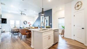 A modern kitchen with a central island, white cabinetry, and a pendant light. - New Lux Home Steps to AT&T + Globe Life w/ Parking (Arlington)