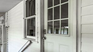 A white door with a window, a doorbell, and a welcome mat.