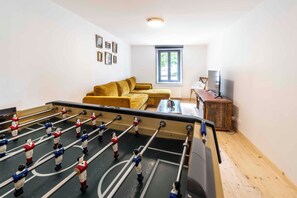 A room with a foosball table, a sofa, a television, and a window. - Gîte L'instant Vosges, private wellness area (Aydoilles)
