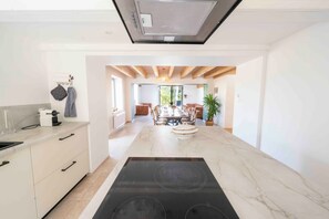 Una cocina moderna con una isla central, un comedor con mesa y sillas, y vistas al exterior.