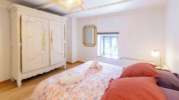 A bedroom with a bed, a wardrobe, a window, and a lamp.
