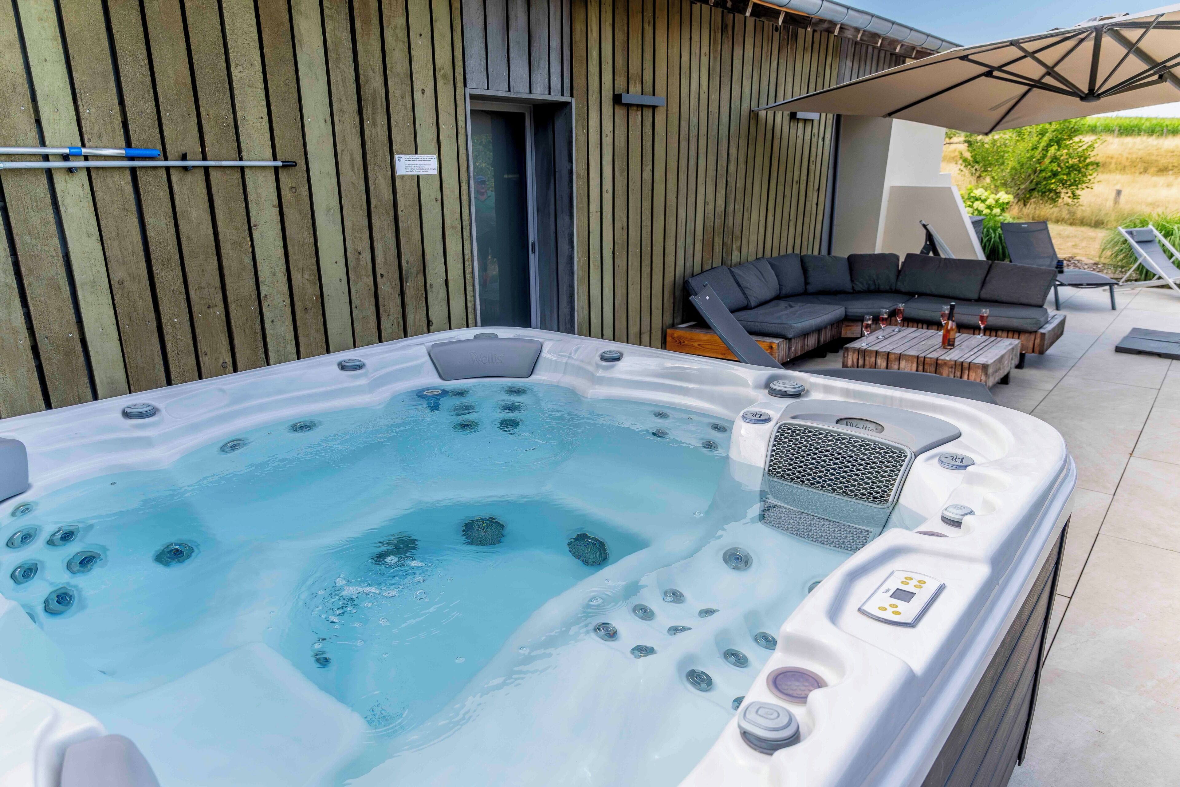 Un bain à remous doté d’un panneau de commande, entouré de mobilier d’extérieur et d’une terrasse en bois.