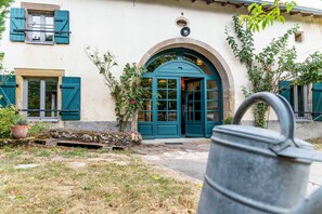 Un bâtiment doté d’une grande entrée en arc de cercle, d’une plante en pot et d’un baril en métal au premier plan.