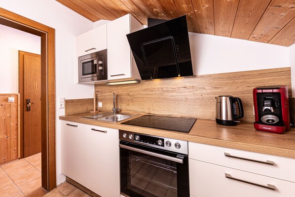 Une cuisine moderne dotée d’un plan de travail en bois, d’appareils électroménagers en acier inoxydable et d’un four encastré.