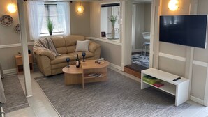 A living room with a beige sofa, a coffee table, a TV, and a patterned rug.