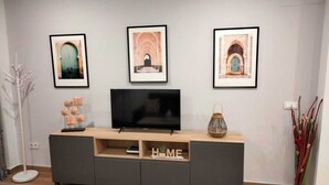 Un soggiorno moderno con un'unità di intrattenimento grigia, una TV a schermo piatto e tre quadri appesi al muro.