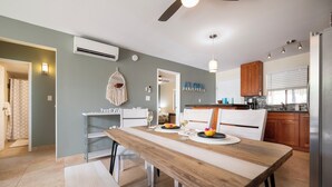 A modern kitchen with a wooden dining table, built-in appliances, and a hanging macrame light fixture.