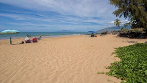 A beach with people, umbrellas, and a clear sky.