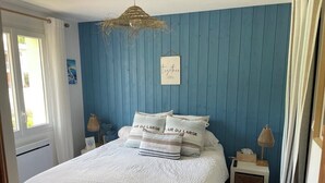 A bedroom with a bed, a nightstand, a hanging light, and a blue wall.