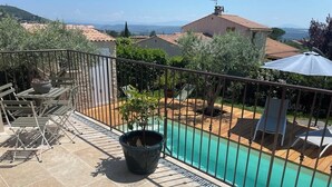 A balcony with a pool, outdoor furniture, and potted plants.