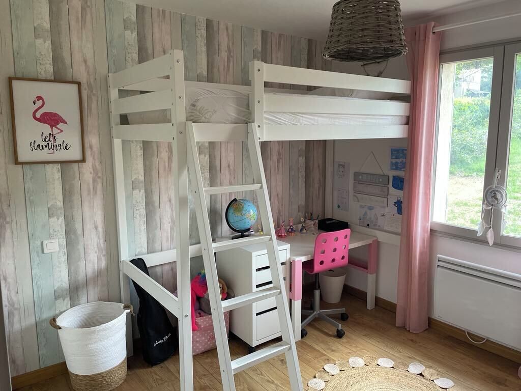 Een stapelbed met een bureau en stoel, een wereldbol en een rieten mand.