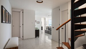 Un interno moderno con una scala, un corridoio che conduce a una zona giorno e vista all'esterno.