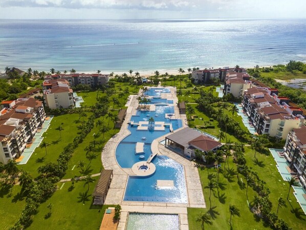 A resort with multiple swimming pools, a central water feature, and beachfront views.