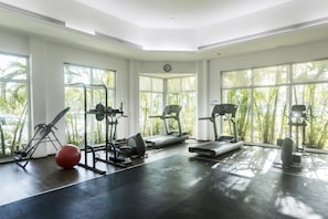 A gym with cardio machines, weight equipment, and a red exercise ball.