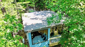 Een boomhut met een blauwe buitenkant, een raam en een hangstoel.