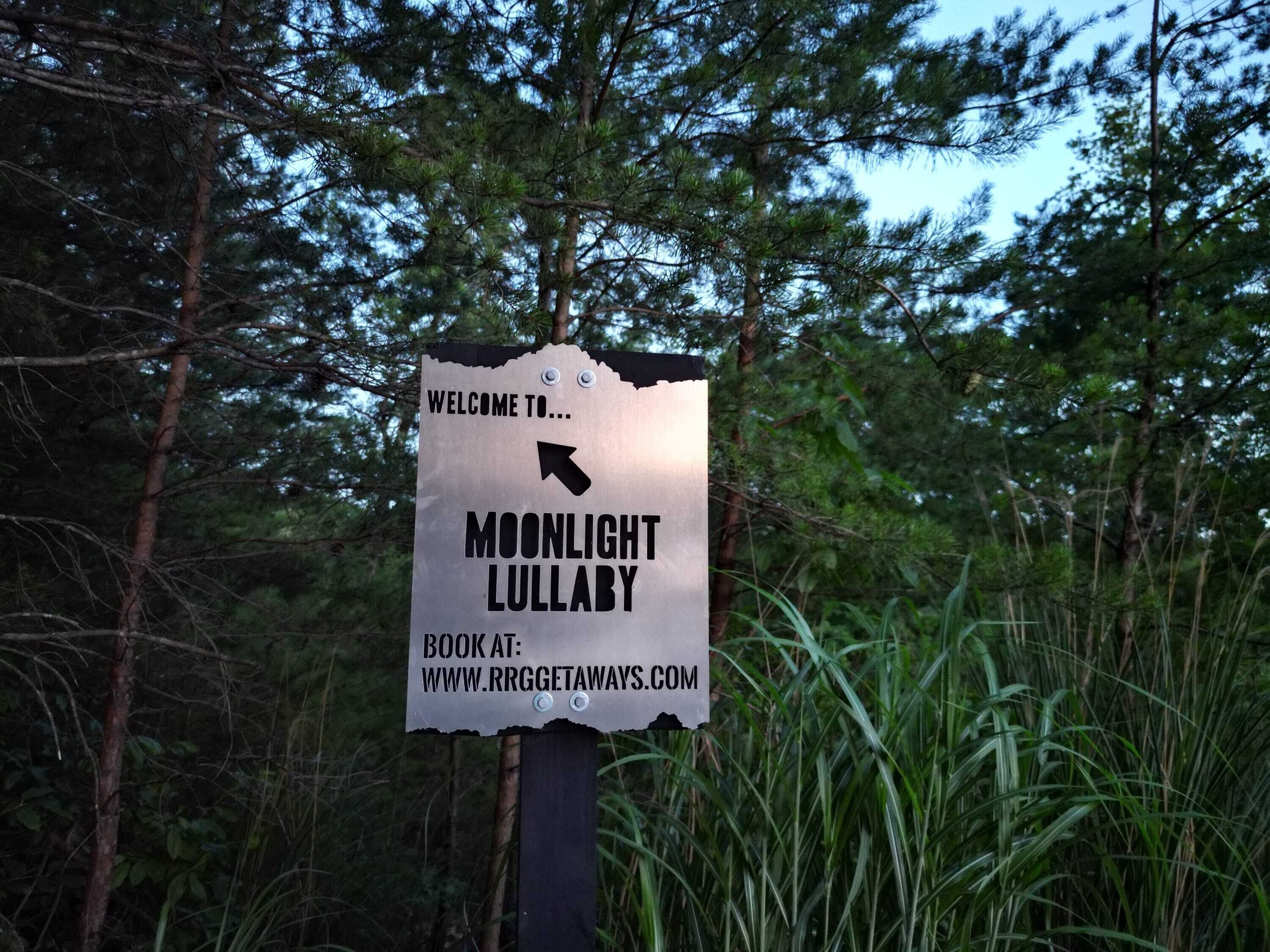 A signpost with a welcome message to Moonlight Lullaby, directing to book at www.rrgggetaways.com.