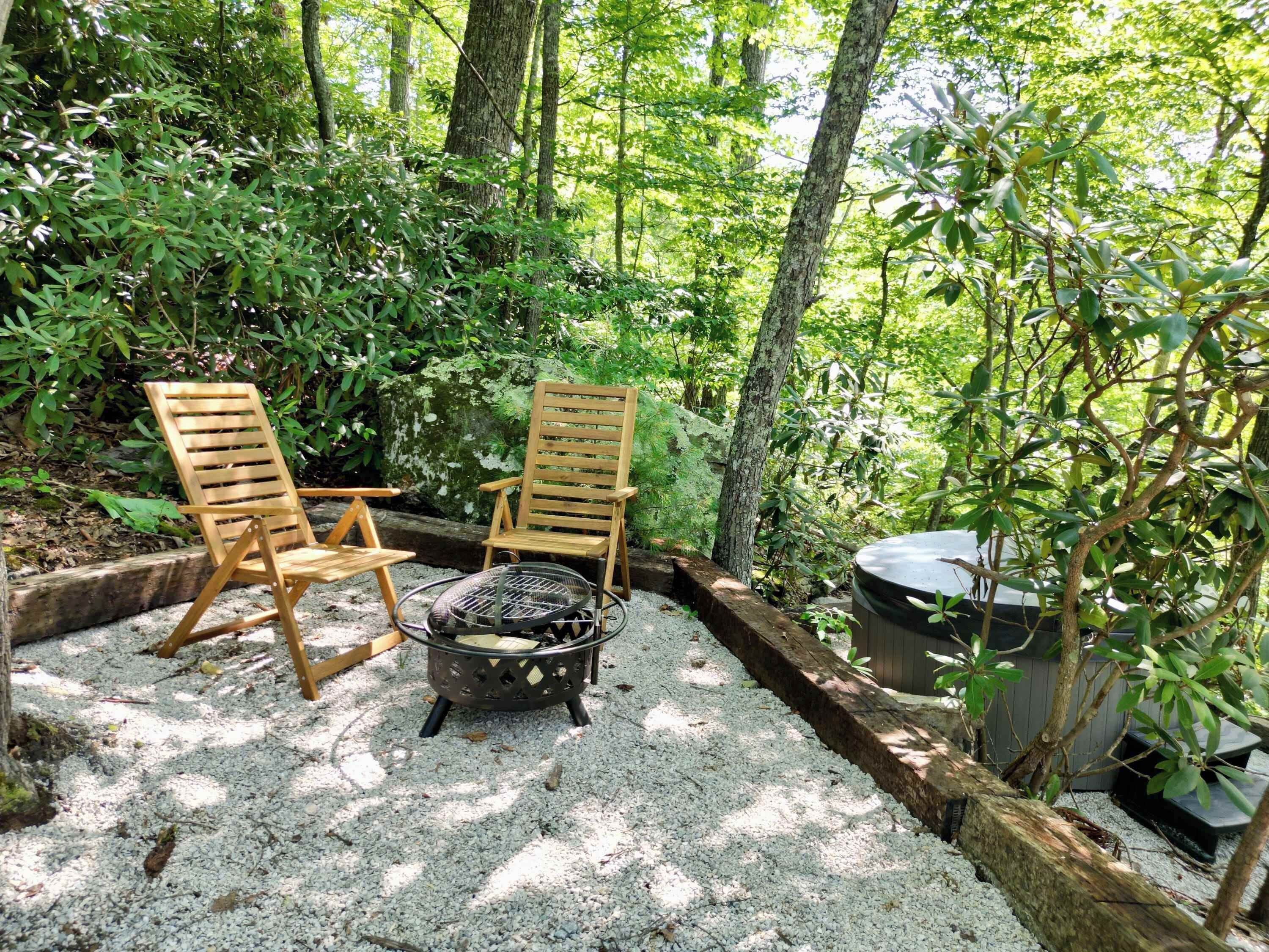 A secluded outdoor seating area with two wooden chairs and a fire pit.