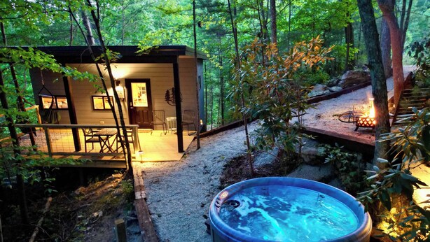 Een chalet met een hottub, omgeven door bomen en een terras.