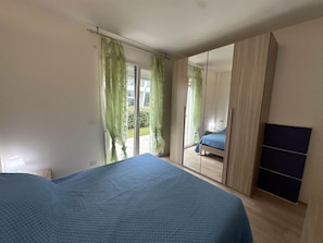 Un dormitorio con cama, armario y puerta corrediza a un balcón.