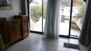 Ein Zimmer mit einer Schiebetür zum Patio, einem Holzschrank und einem gerahmten Bild an der Wand.