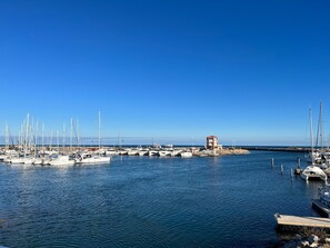 A marina with multiple boats docked, a small tower structure, and calm water. - Le Barcarès - Charming 2BR Villa with Parking, Near Beach and Port (Le Barcarès)