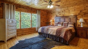 A wooden cabin bedroom with a bed, dresser, and a ceiling fan. - View To Remember, Stunning Mountain Views, Hot Tub, Game Room, Near Pigeon Forge (Sevierville)