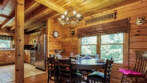 A wooden cabin interior with a dining area, kitchen, and a sign reading "The Gathering Place". - View To Remember, Stunning Mountain Views, Hot Tub, Game Room, Near Pigeon Forge (Sevierville)