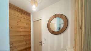 Un pasillo con paneles de madera, una puerta blanca y un espejo redondo en la pared.