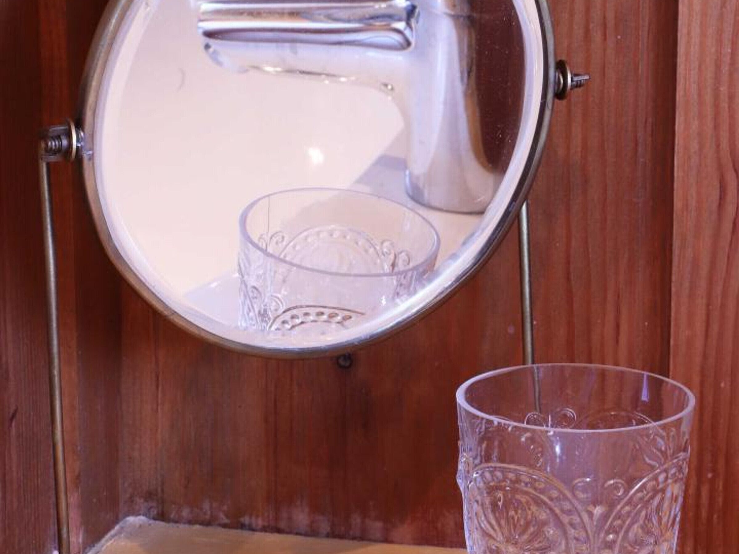 Un objet rond et métallique, doté d’une anse, qui pourrait être une bouilloire ou une casserole, fixé à un mur en bois.