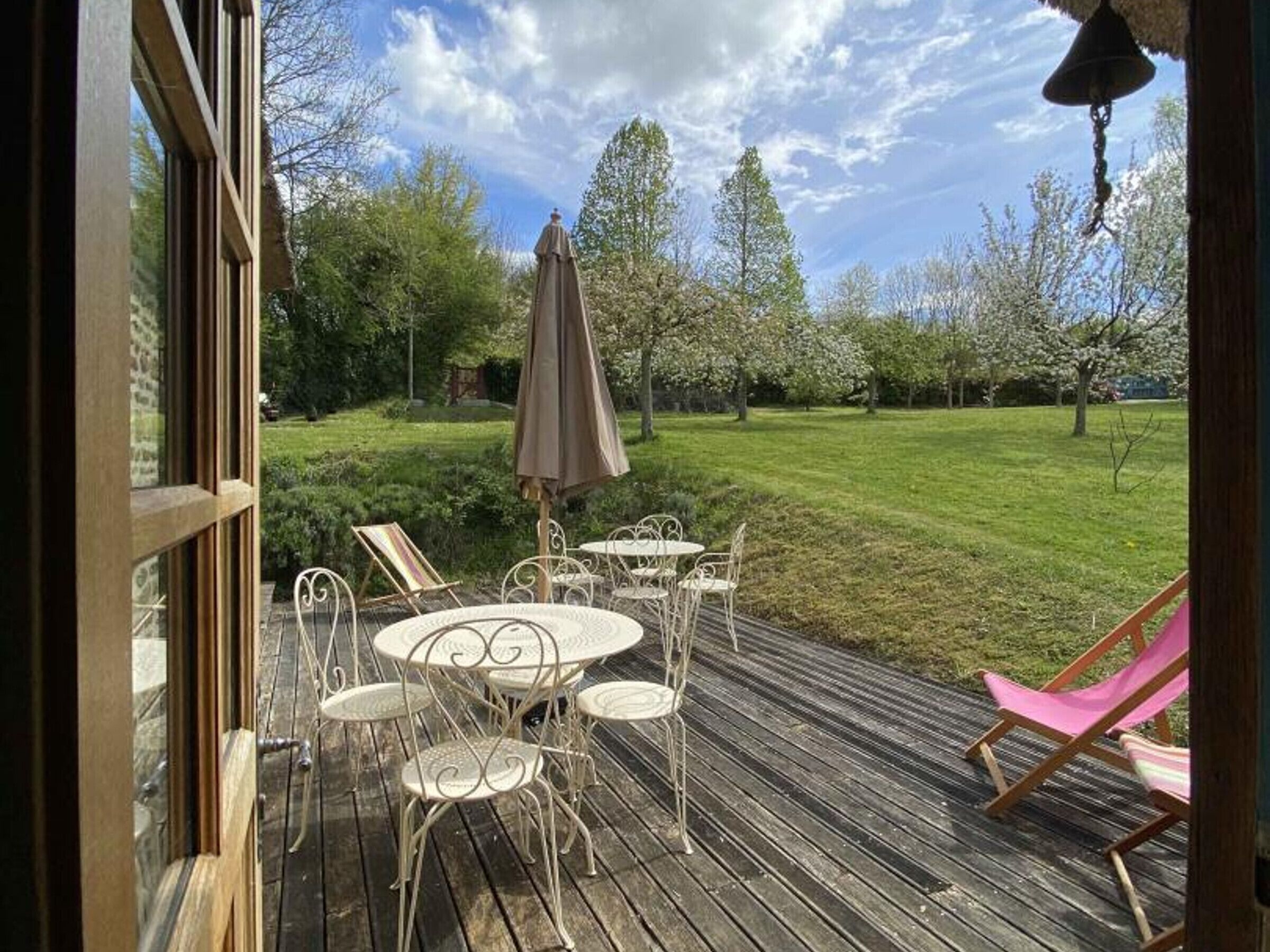 Eine Holzterrasse mit Gartenmöbeln, darunter ein Tisch und Stühle sowie ein Sonnenschirm.