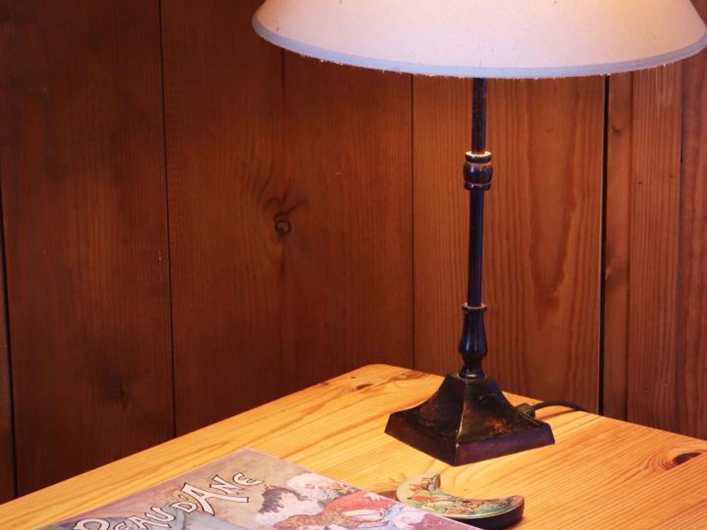 Une table en bois, une lampe et un livre.