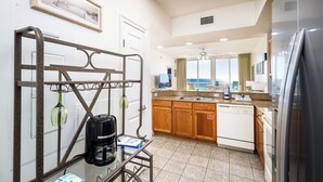 Una cucina moderna con una moka, un tavolo in vetro, mobili in legno e vista sull'oceano.